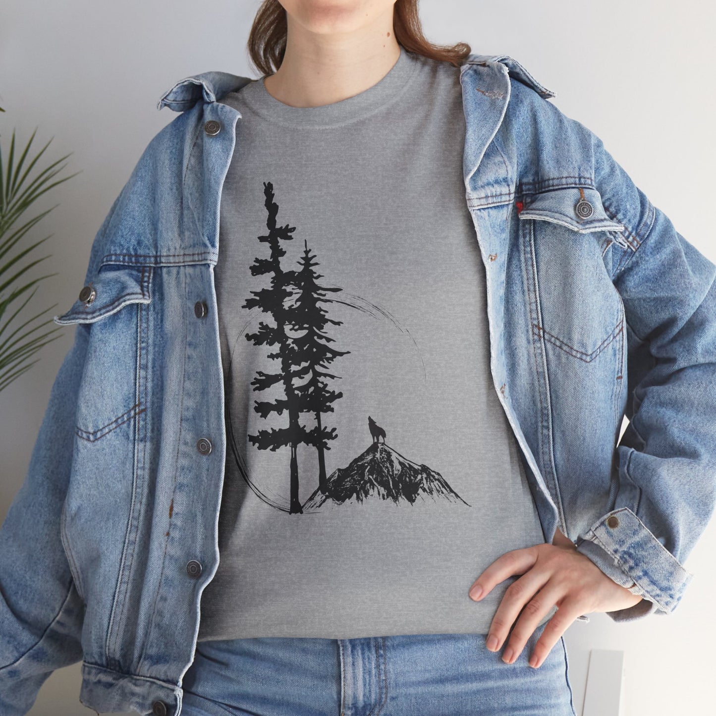 Person wearing a gray t-shirt with a tree and mountain design, paired with a denim jacket.