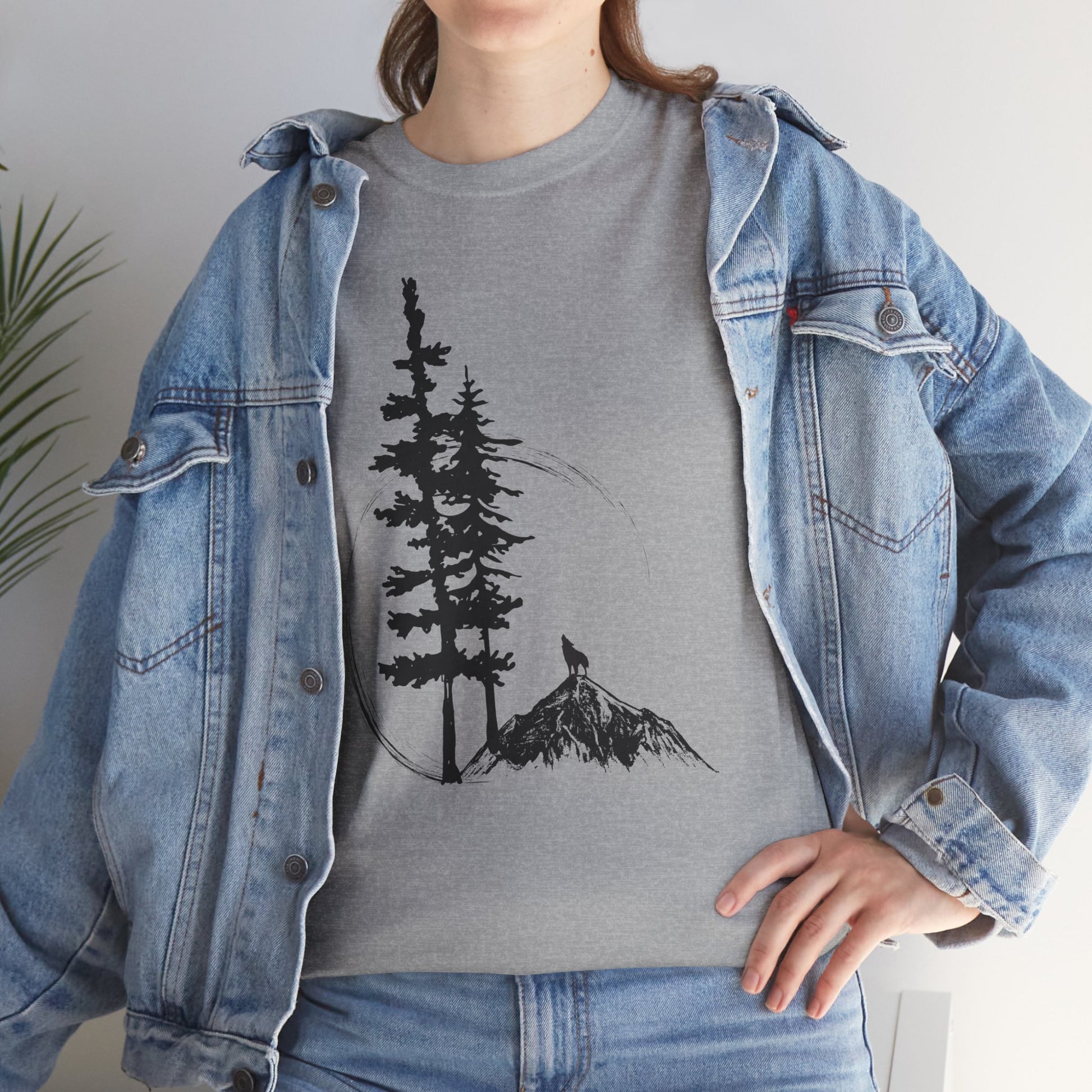 Person wearing a gray t-shirt with a tree and mountain design, paired with a denim jacket.